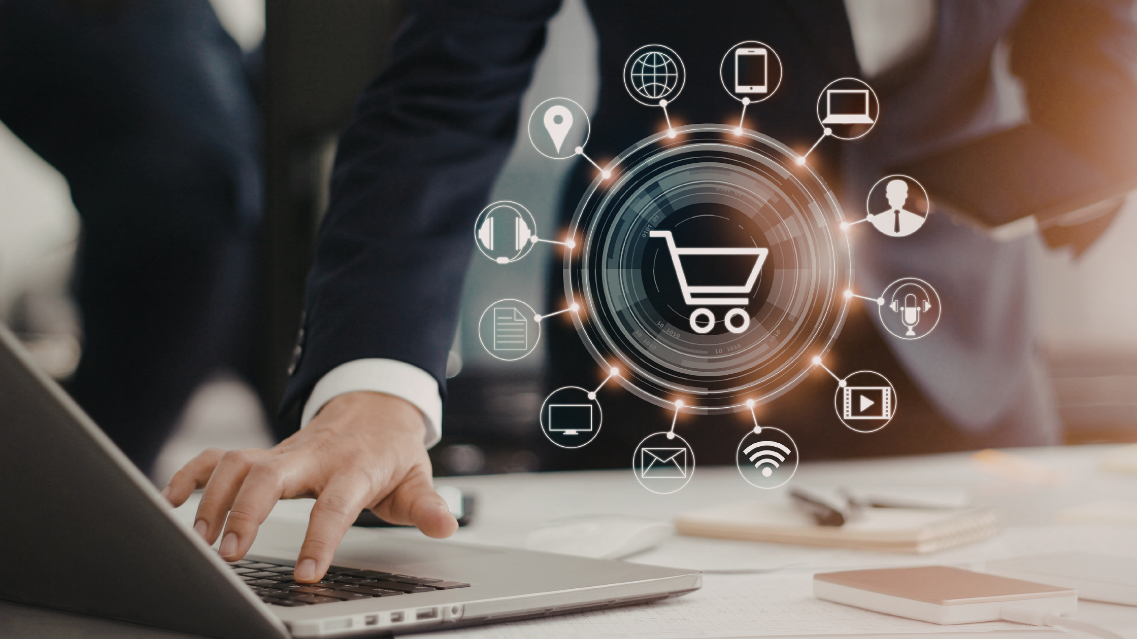 A businessman using a laptop with a digital shopping cart interface and related icons representing e-commerce activity and online services.